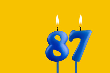 Blue candle number 87 - Birthday on yellow background