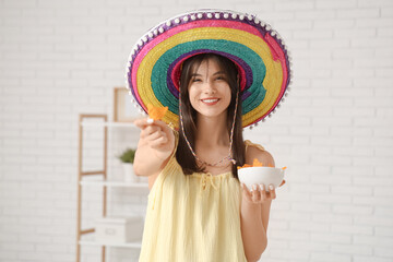 Young woman in sombrero with nachos at home. Cinco de Mayo celebration