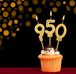 Number 950 birthday candle - Cupcake on black background with out of focus lights