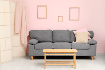 Comfortable sofa with cushions and coffee table in interior of living room