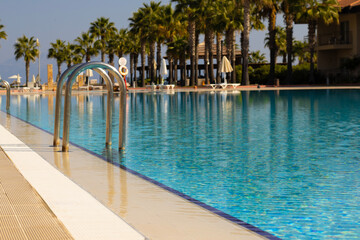 A large, inviting pool at a summer resort hotel, epitomizing luxury and relaxation.