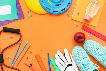 Frame made of sneakers, frisbee, apple, expander and different stationery on orange background