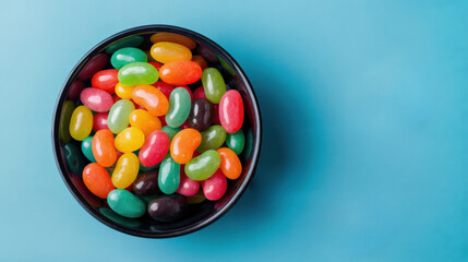 A bowl of colorful jelly beans isolated against a blue background. Ample copy space.