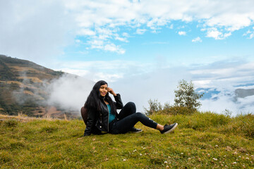 Hermosa foto de una feliz viajera hispana con una mochila en la cima de montañas verdes.cielo dia.Concepto de viaje turismo.