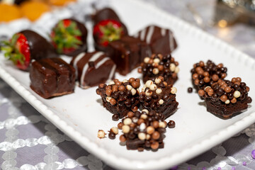 Plate full of an assortment of  desserts such as cookies, chocolate covered strawberries, mini cannoli and more. 