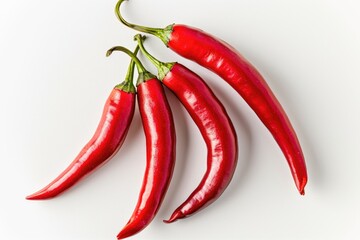 A trio of bright red hot peppers sit on a white surface, waiting to be used in a recipe