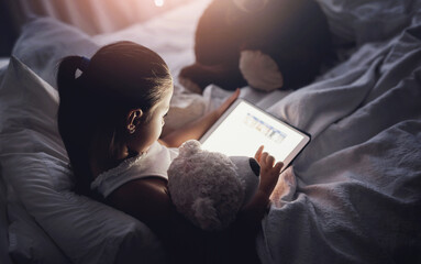 Tablet, reading and kid at night with ebook, story and youth game with cartoon and language app. Tech, teddy bear and young girl with scroll, relax and evening screen time at home in bed online