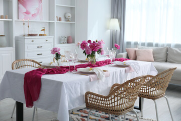 Beautiful table setting with pink accent and rattan chairs in dining room