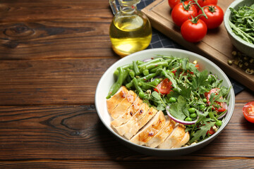 Healthy meal. Tasty salad and chicken breast in bowl on wooden table, space for text