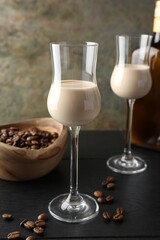 Coffee cream liqueur in glasses and beans on black wooden table