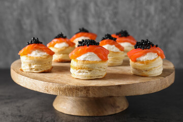 Delicious puff pastry with cream cheese, salmon and black caviar on grey table