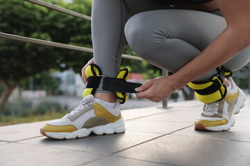 Woman putting on ankle weights outdoors, closeup