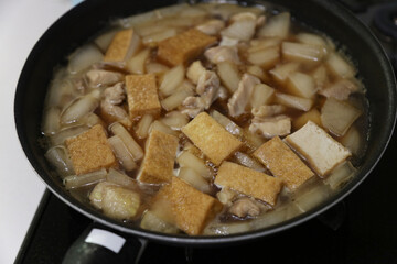 鶏もも肉と大根と厚揚げの煮物を作る様子