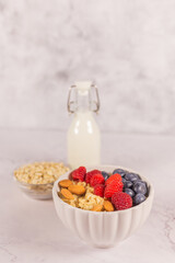 Oatmeal cereal porridge with fresh berries and nuts in white bowl. Healthy breakfast. Dietary. Top view on white marble stone table. 
