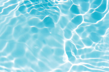 Blue water with ripples on the surface. Defocus blurred transparent blue colored clear calm water surface texture with splashes and bubbles. Water waves with shining pattern texture background.