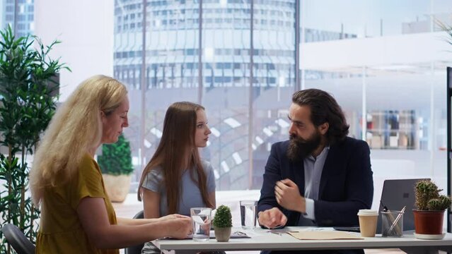 Financial adviser providing customers with informative leaflets on budget management. Consultant in office assisting family members in setting up investment accounts, camera B