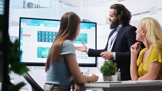 Financial adviser presents market analytics to customers using large display, explore best practices for building portfolio. Broker agent showing stock exchange charts to mother and daughter, camera A