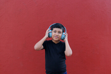 9-year-old dark-skinned Latino boy uses noise-isolating headphones due to the sensitivity caused by...