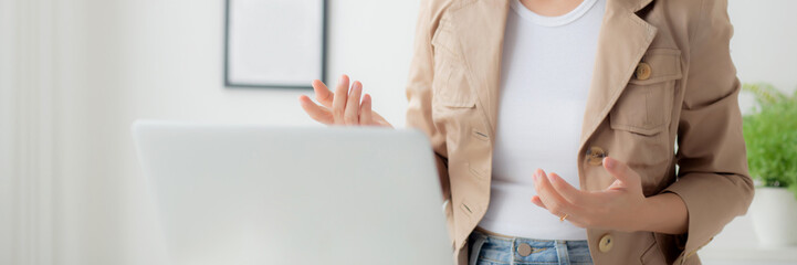 Young asian businesswoman wearing headset video call and explain conference online at home, woman wearing headphone meeting and talking for working from home, business and communication concept.