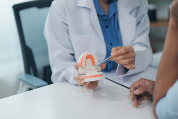Dentist consultation - patient visit at the dental clinic office. Female dentist wearing dentures to explain teeth Recommend guidelines for orthodontics Dentist giving advice on patient's condition