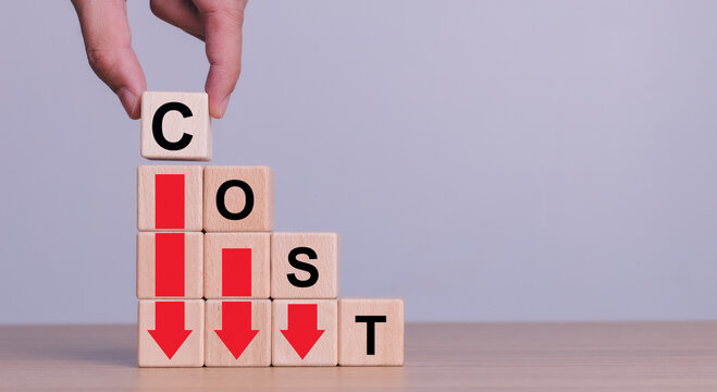 Cost reduction concept. Optimize manufacturing management. Optimization, Strategy, Economic cost savings. Hand puts wooden cube with words cost and green down arrows. cost icon on virtual screen.