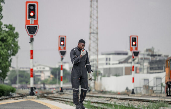 A railway signal maintainer communicates via radio while walking along the tracks