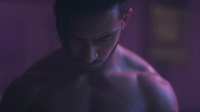 Muscular man holding nunchucks and looking straight at the camera