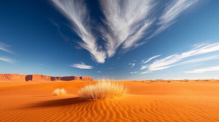 A stunning desert landscape with vibrant orange sand dunes, dramatic clouds, and a clear blue sky providing a breathtaking natural scene.