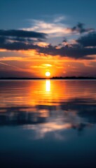 Fototapeta premium Stunning sunset over calm lake with vibrant colors reflecting in the water, creating a serene and peaceful landscape scene.
