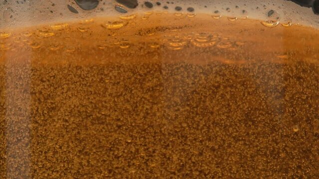 Light beer is poured into a glass close-up. Beer bubbles and foam splash in the mug. Refreshing amber beer drink in slow motion