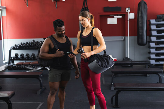 Fit African American man and young Caucasian woman at the gym