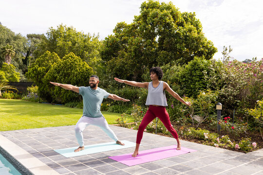 Biracial couple practicing yoga outdoors, with copy space - Powered by Adobe