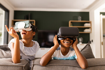 Teenage biracial brother and sister enjoy VR headsets at home