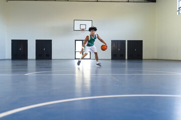 A young biracial man plays basketball indoors