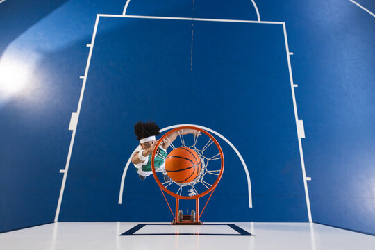 Young biracial man playing basketball indoors, with copy space