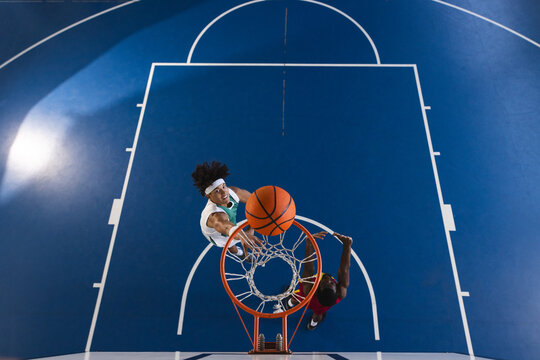 Young biracial man plays basketball indoors