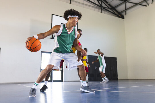 Young African American man plays basketball indoors