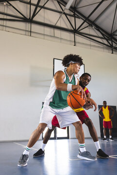 Young African American man guards a biracial man in a basketball game
