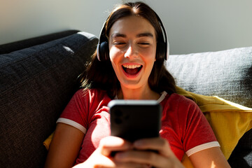 Teenage Caucasian girl enjoys music on her phone at home