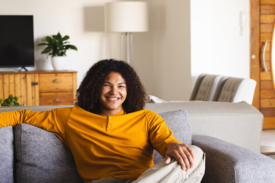 Young Biracial man relaxing on a couch at home, with copy space