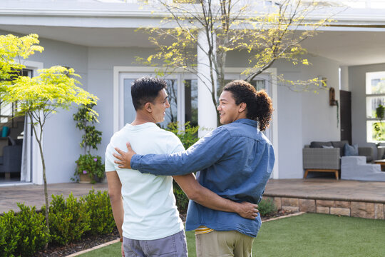 Diverse gay couple embraces in a home garden
