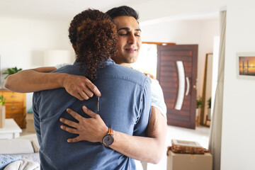 Gay, biracial couple embracing in a new home