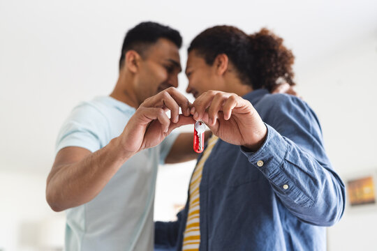 Diverse gay couple holding house keys together, with copy space