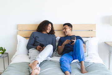 Gay biracial couple relaxes in a cozy bedroom setting