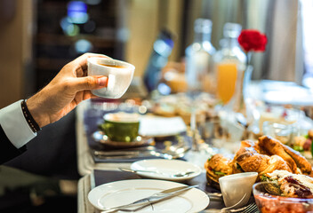 Hand holding coffee cup. Sweet food breakfast restaurant. table with croisant pastries.