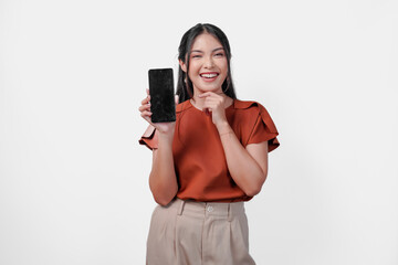 Beautiful young Asian woman in brown shirt smiling while showing the copy space on phone screen,...