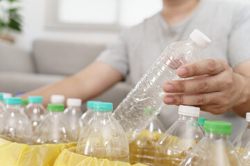 Home recycle eco green zero concept Man throwing empty plastic bottle in recycling bin with yellow garbage bags at home