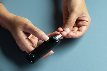 Woman's hands checking diabetes and hyperglycemia with digital blood sugar meter. Healthcare and medical concept