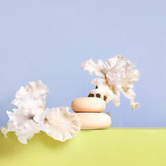 Wood stones and white iris flowers on yellow podium. Concept scene stage showcase for new product, banner, promotion sale, cosmetic, presentation