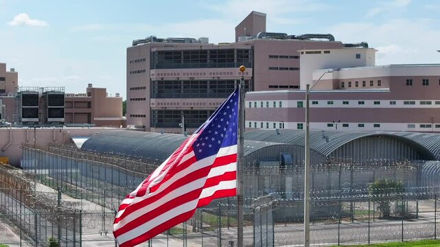 American flag waving in front of high security prison. Jail, inmate, detention center theme. United States judicial system.